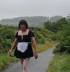 Transvestitenmädchen give einer öffentlichen Gasse im Regen